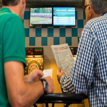 Joueur étudiant les courses de chevaux avec le journal hippique 